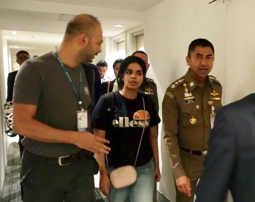 In this January 7, 2019, file photo released by the Immigration Police, chief of Immigration Police Maj. Gen. Surachate Hakparn (right) walks with Rahaf Mohammed Alqunun before leaving the Suvarnabhumi Airport in Bangkok.
