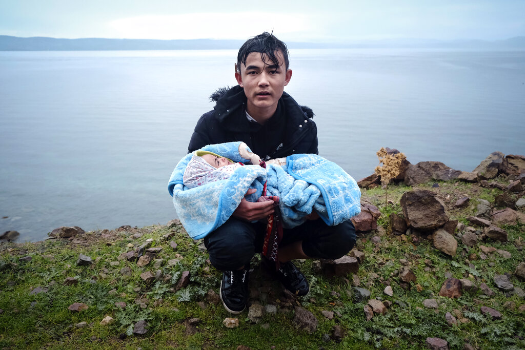A migrant holding a baby pauses on the side of the road while walking to the village of Skala Sikaminias, on the Greek island of Lesbos, after crossing on a dinghy the Aegean sea from Turkey on Thursday