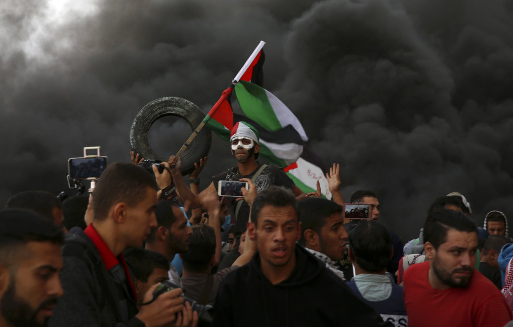 Protesters chant slogans as others burn tires near the fence of the Gaza Strip border with Israel on Friday.