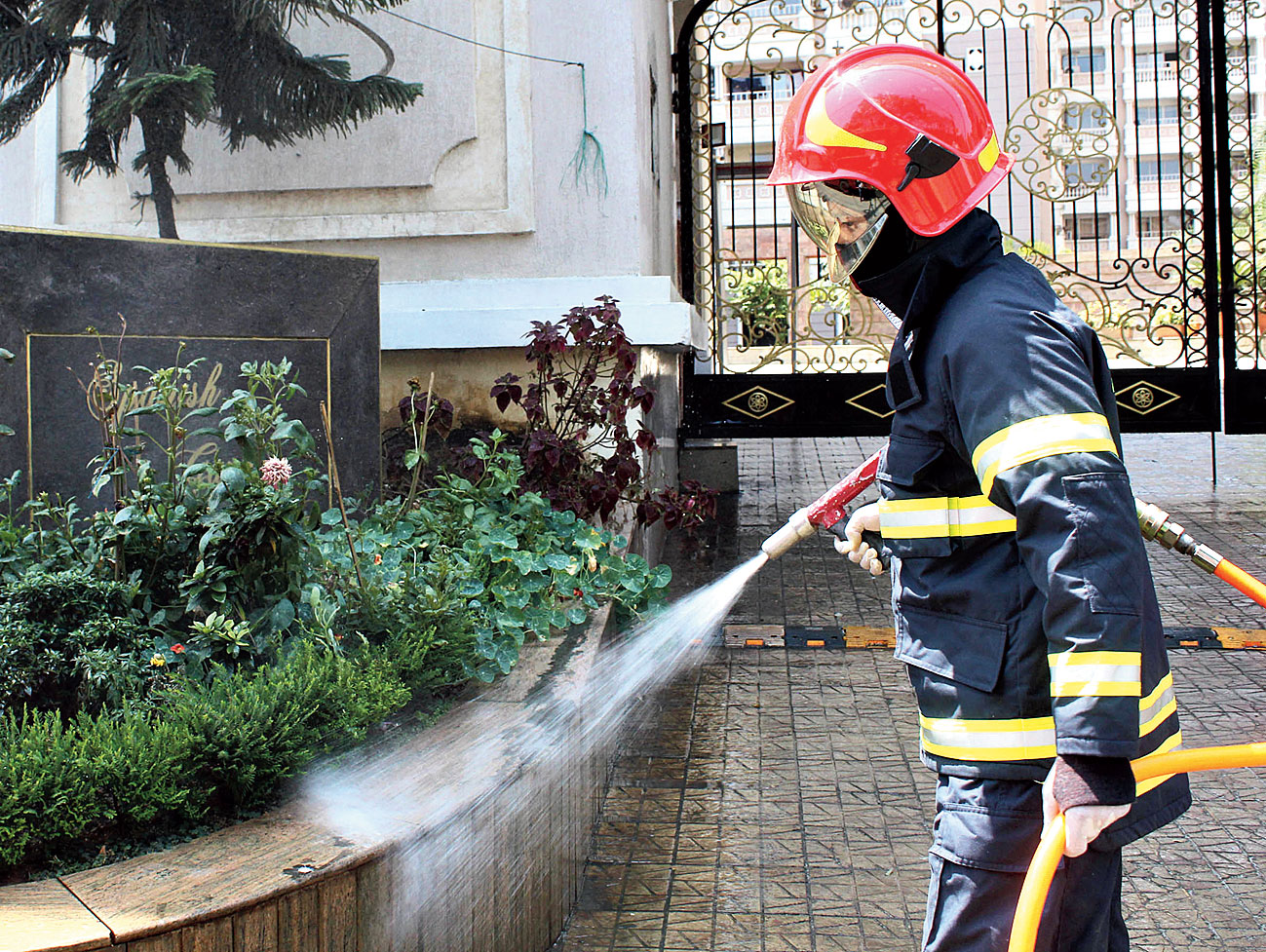 A fire and emergency services worker sprays disinfectant at the entrance of the apartment in Guwahati. 
