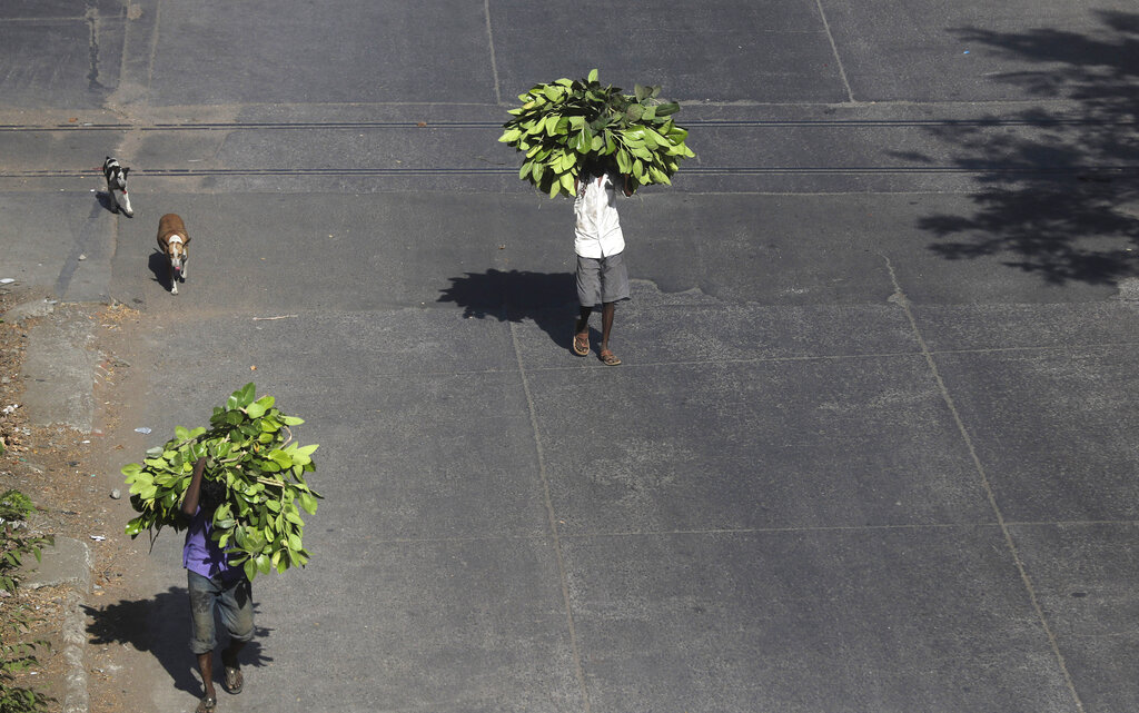 People walk carrying fodder on their heads during a lockdown in Mumbai, on Friday, May 22, 2020