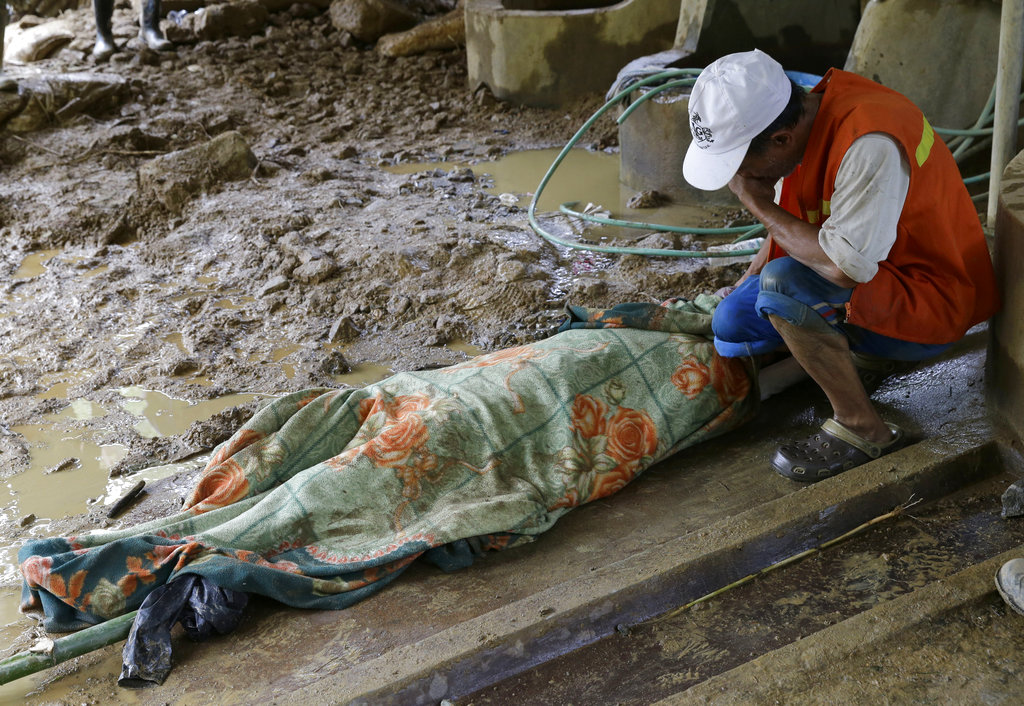 Pio Badangayon cries as she sits next to the body of her son-in-law Edwin Banawol after it was retrieved by rescuers in Itogon in the Benguet province in northern Philippines.