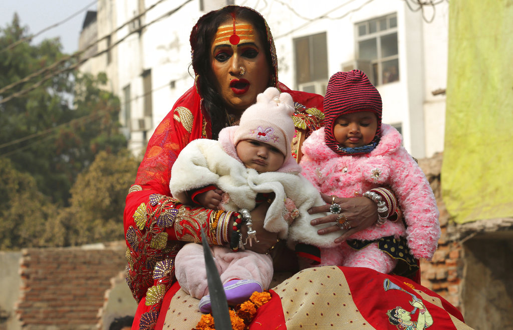 Lakshmi Narayan Tripathi, head of the Kinnar Akhara for transgenders, holds two infants to bless them while riding on a camel during a procession towards the Sangam.