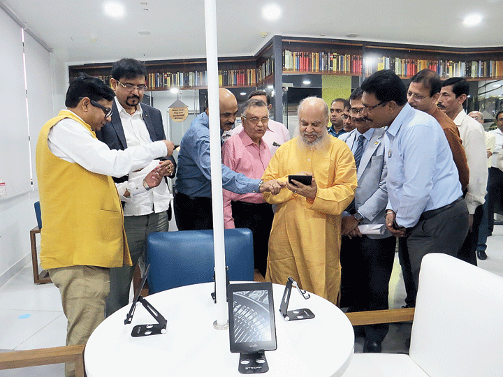 Debashis Sen shows minister Sujit Bose how to read a digital book on Kindle as artist and BH Block resident Shuvaprasanna too checks out one on the inaugural day of the New Town Library. 