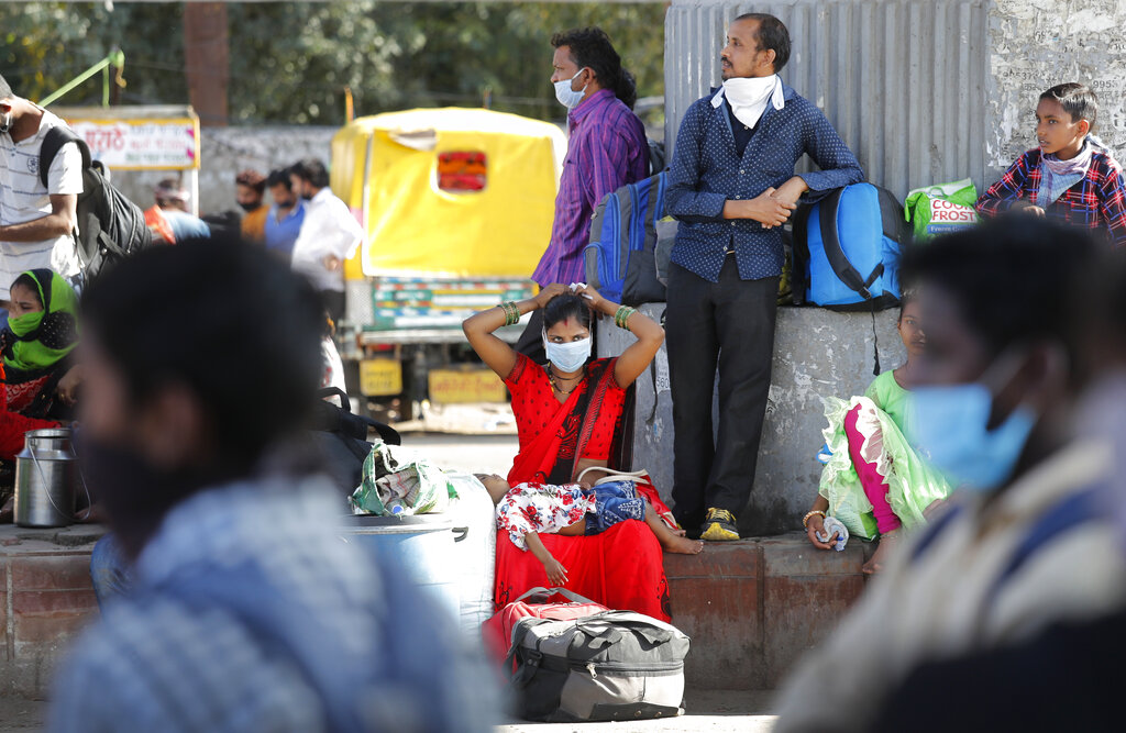 A migrant daily-wage laborer family wait for transportation to travel to their respective villages following a lockdown amid concern over spread of coronavirus in New Delhi, on Friday, March 27, 2020.