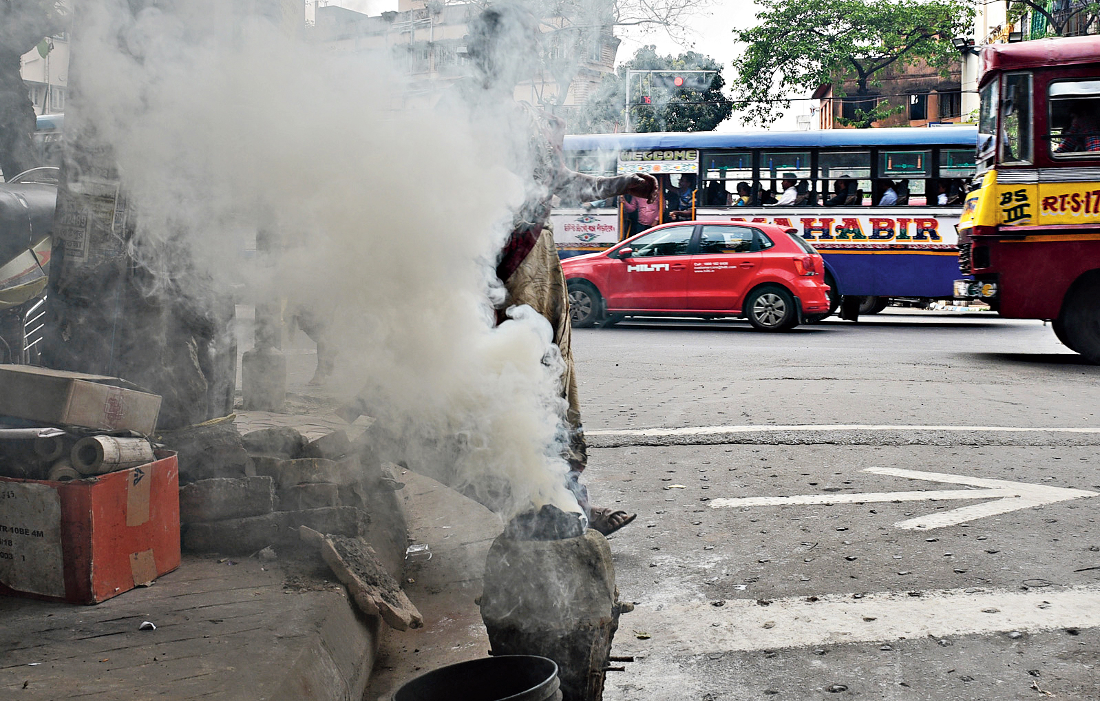 Smoke rises from a coal cooking gas oven on a city road
