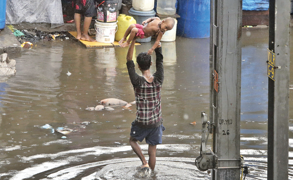 A man holds aloft a child as he plods through a waterlogged street in Mumbai on Tuesday