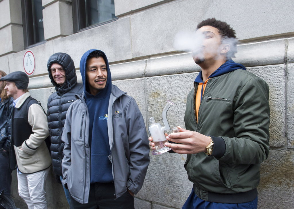 A man smokes from a bong as he waits in line to purchase legal cannabis outside a government cannabis store in Montreal on Wednesday.