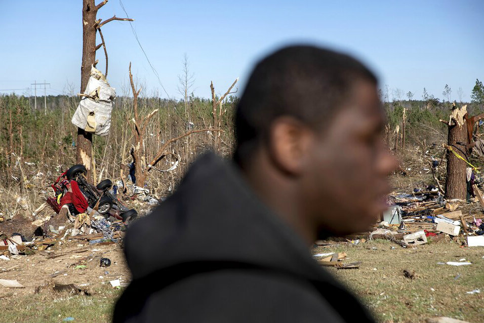Demetria Jones walks through the damaged neighbourhood where he said he lost ten relatives in a tornado in Beauregard, Alabama, on Tuesday.