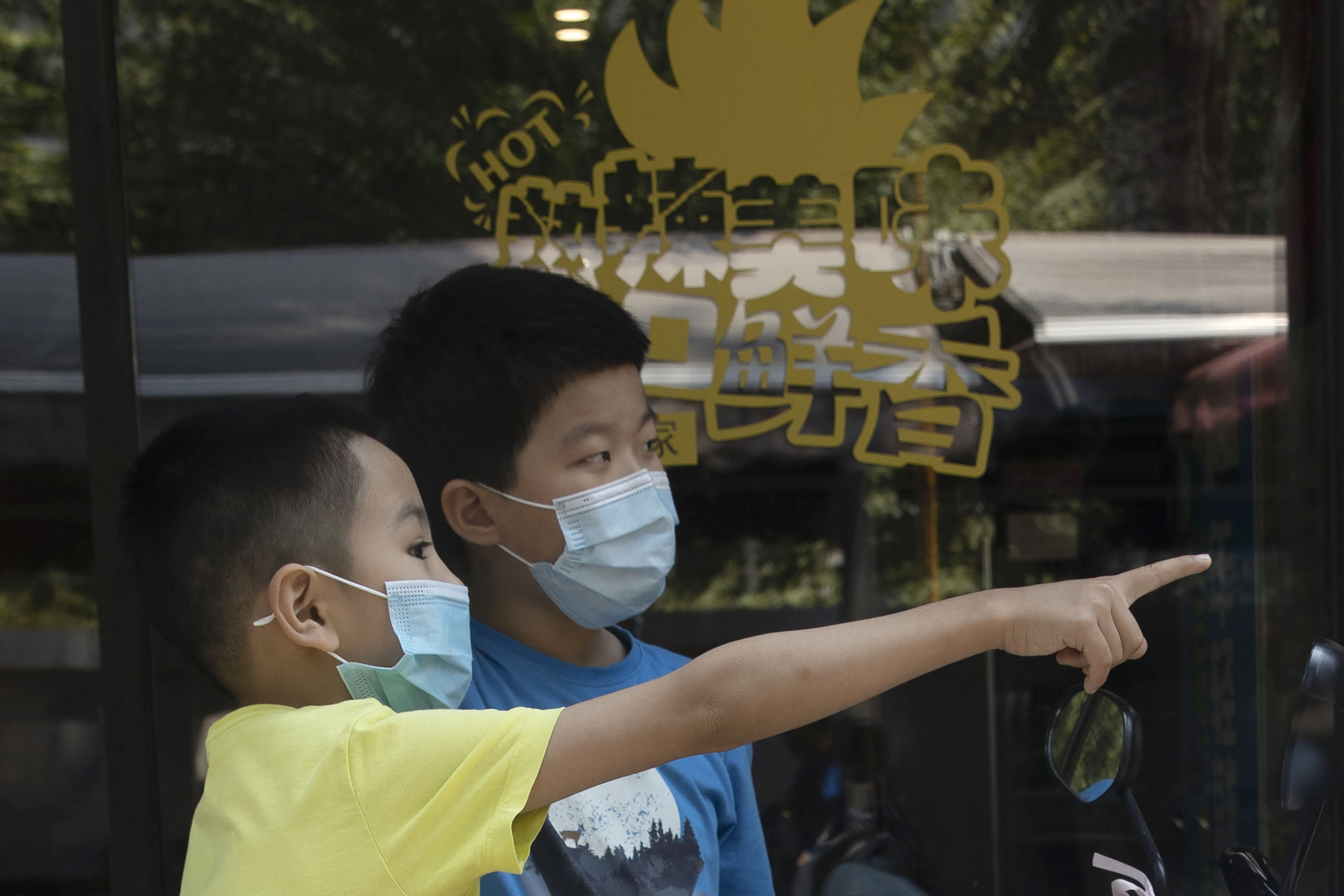 Children wearing masks chat outside a restaurant in Beijing 