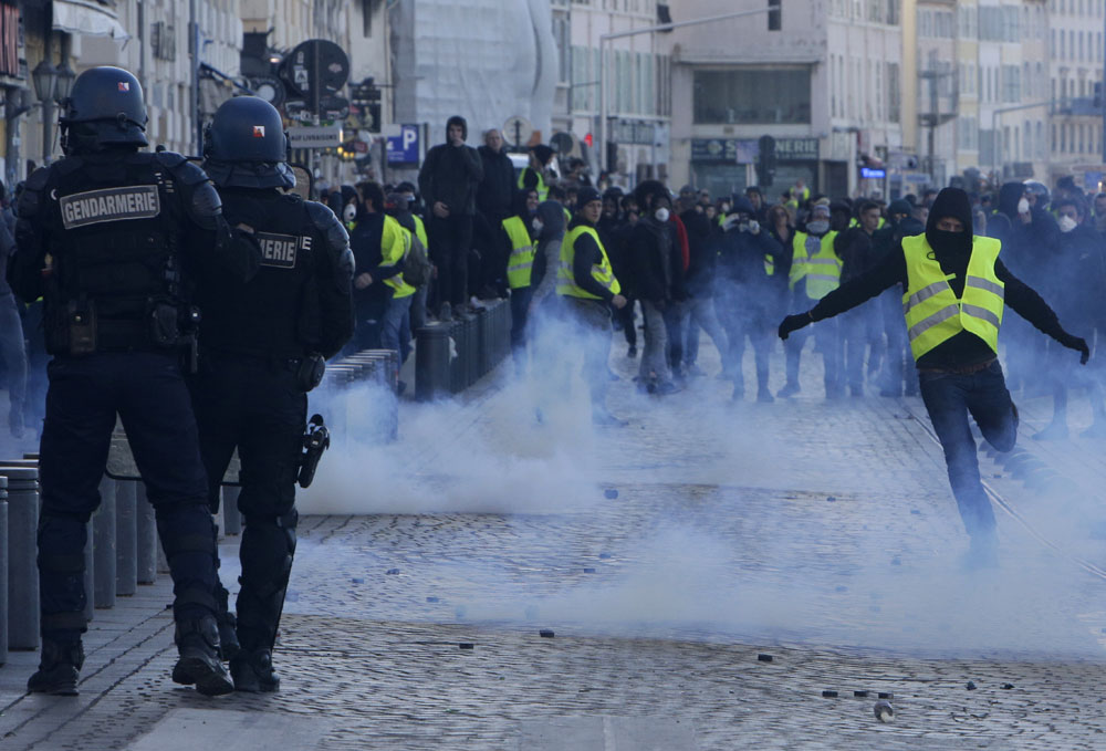 A demonstrator kicks into a tear gas canister during clashes on Saturday, December 8, in Marseille, southern France. French riot police fired tear gas and water cannon in Paris
