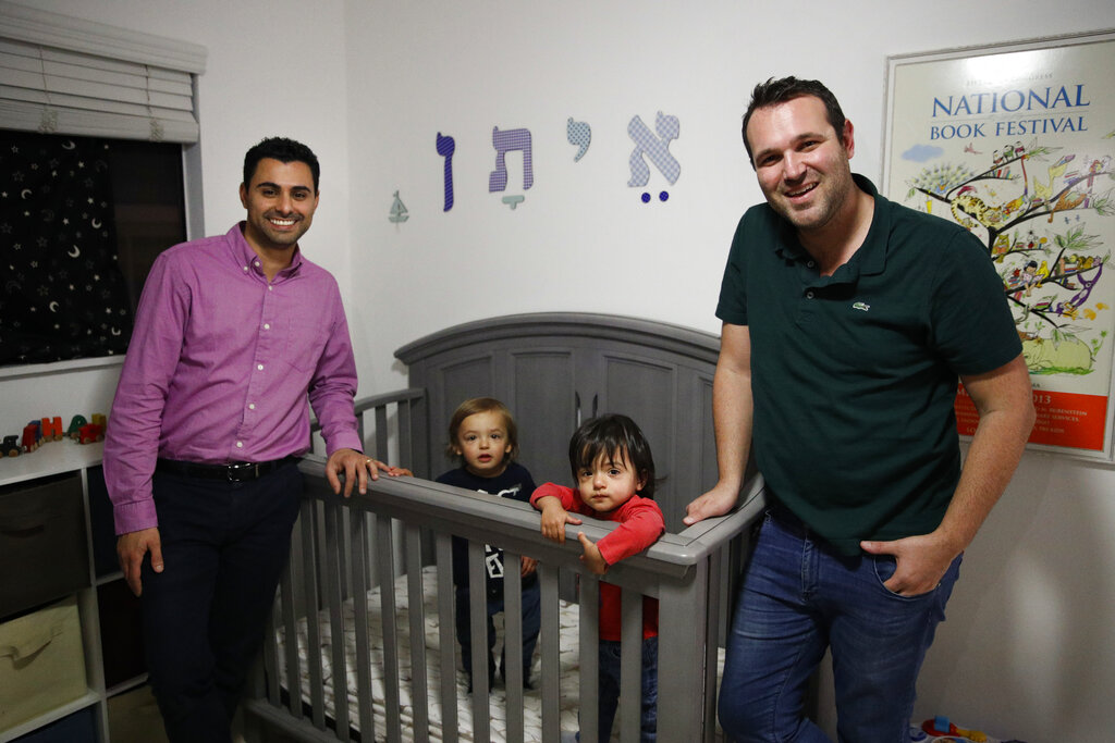 Elad Dvash-Banks (left) and his partner, Andrew, with their twin sons, Ethan (second from right) and Aiden in their apartment in Los Angeles.