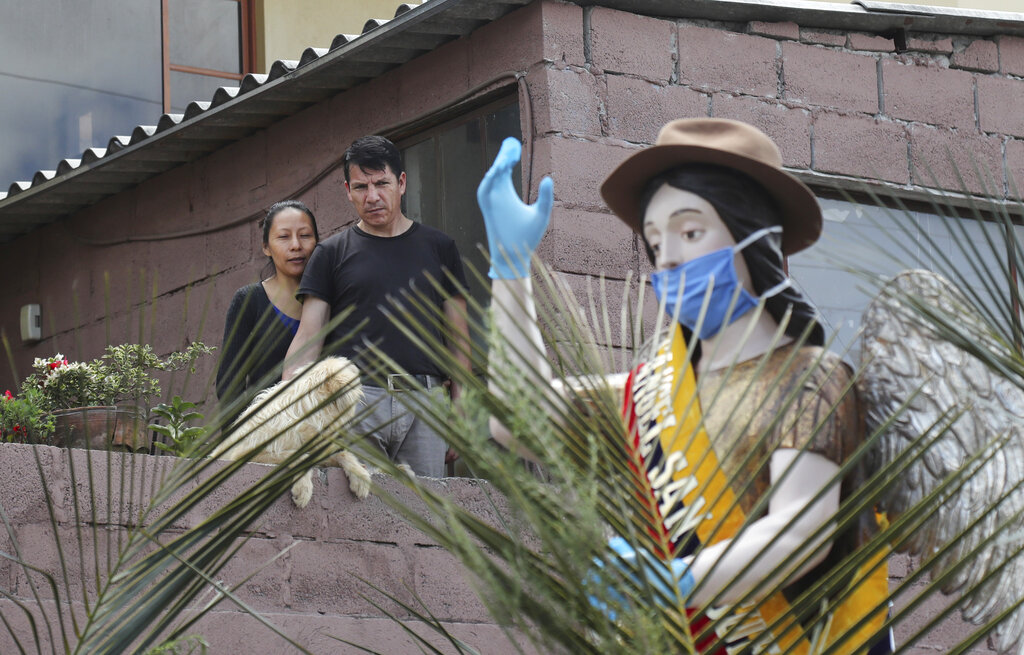 Faithful look at an image of the archangel St. Michael, wearing a mask as required to all inhabitants of the country to prevent the spread of the new coronavirus, during the Palm Sunday procession in Zambiza, near Quito, on Sunday