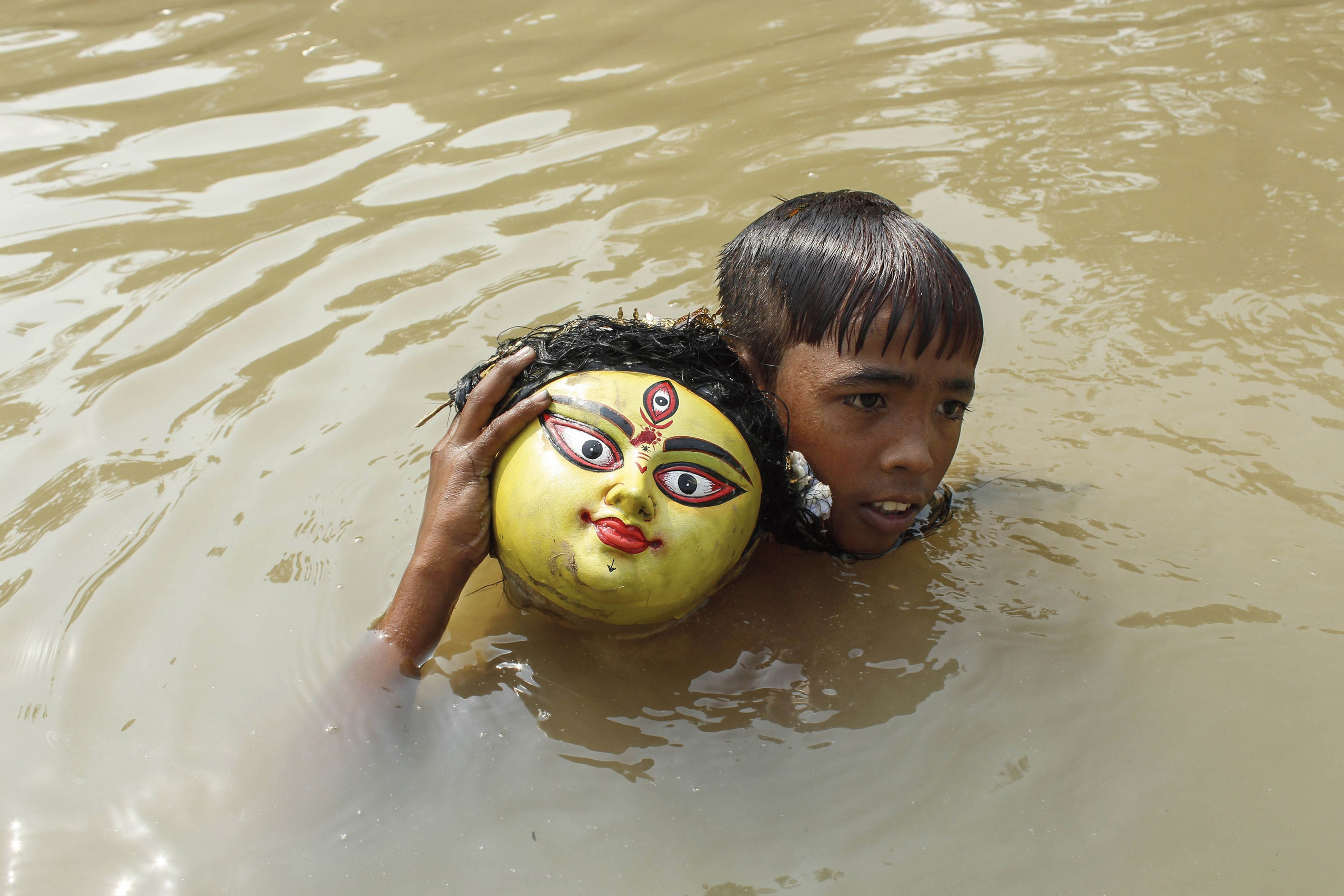 Parting blues: A boy collects the head of a Durga idol after an immersion ceremony in Agartala on Friday.