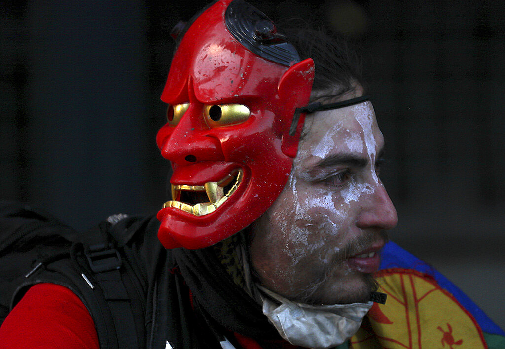 An anti-government protester takes a break during clashes with police in Santiago, Chile, Friday, Dec. 6, 2019