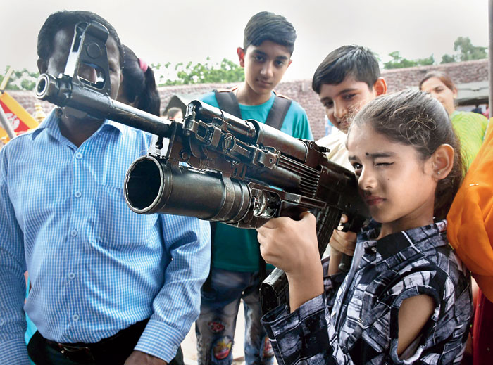 A girl tries her hands on an AK 47 rifle during Know Your Army exhibition organised to mark the Kargil Vijay Diwas in Bhopal on Friday.