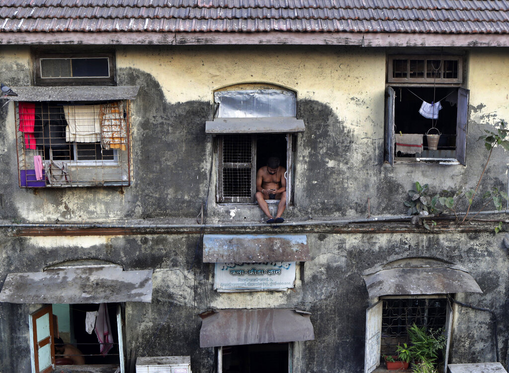 A man sits alone at the window of a Chawl during a lockdown to prevent the spread of the new coronavirus at Lower Parel area in Mumbai, India, Sunday, April 5, 2020