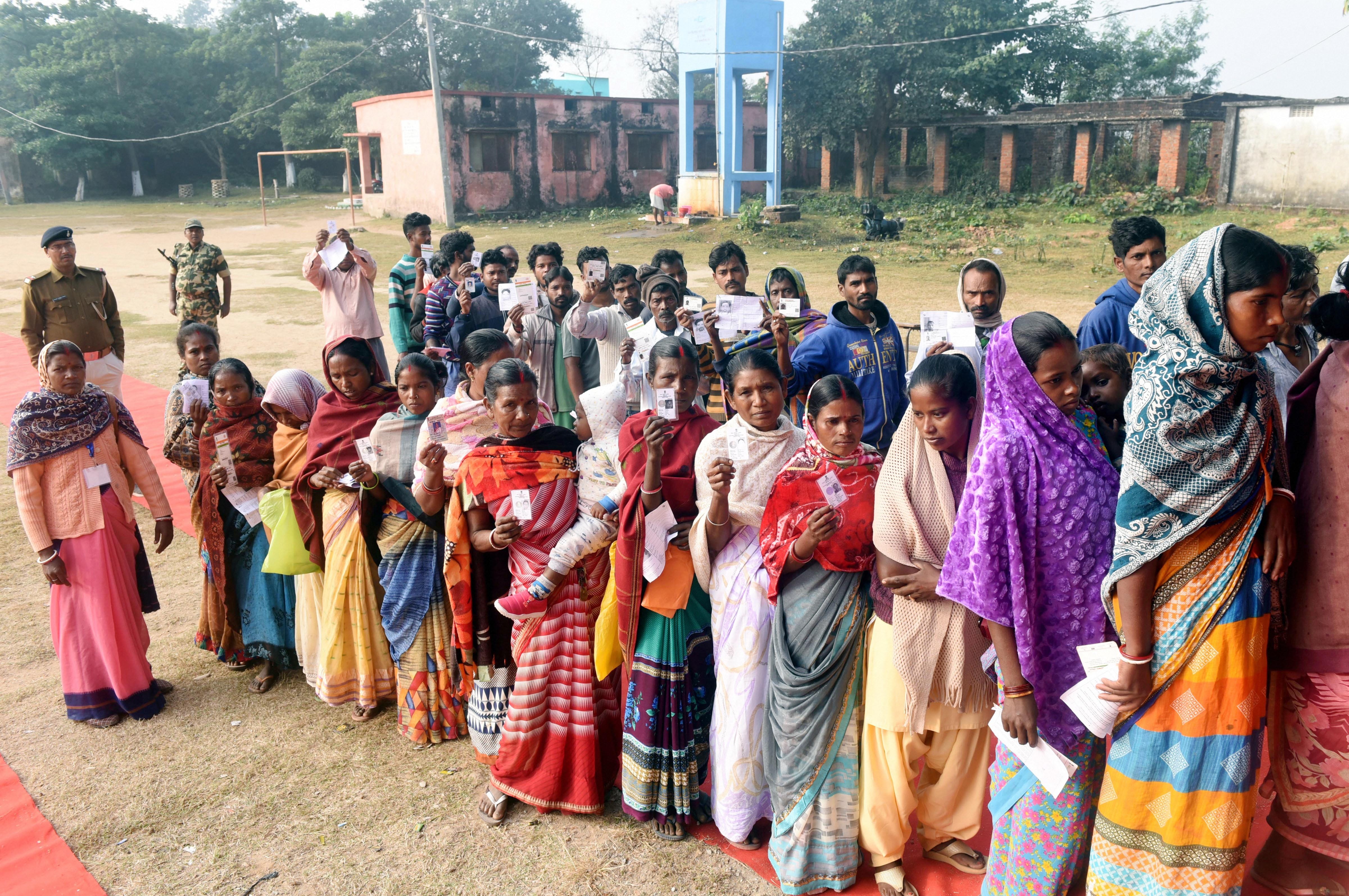 People wait in queues to cast their votes at a polling station during the second phase of Jharkhand Assembly elections at Bundu, 45 kms from Ranchi, Saturday, December 7, 2019