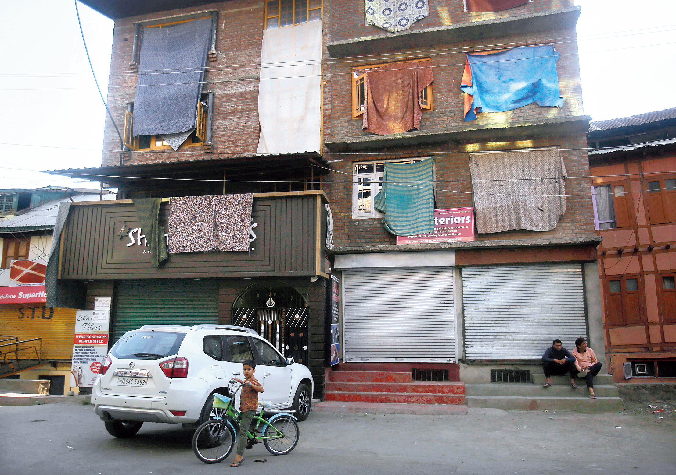 A boy (not the boy mentioned in the accompanying report) stands with his bicycle in front of homes in Srinagar that have covered their windows with sheets as a shield against stone-throwers during a strike on September 12. 