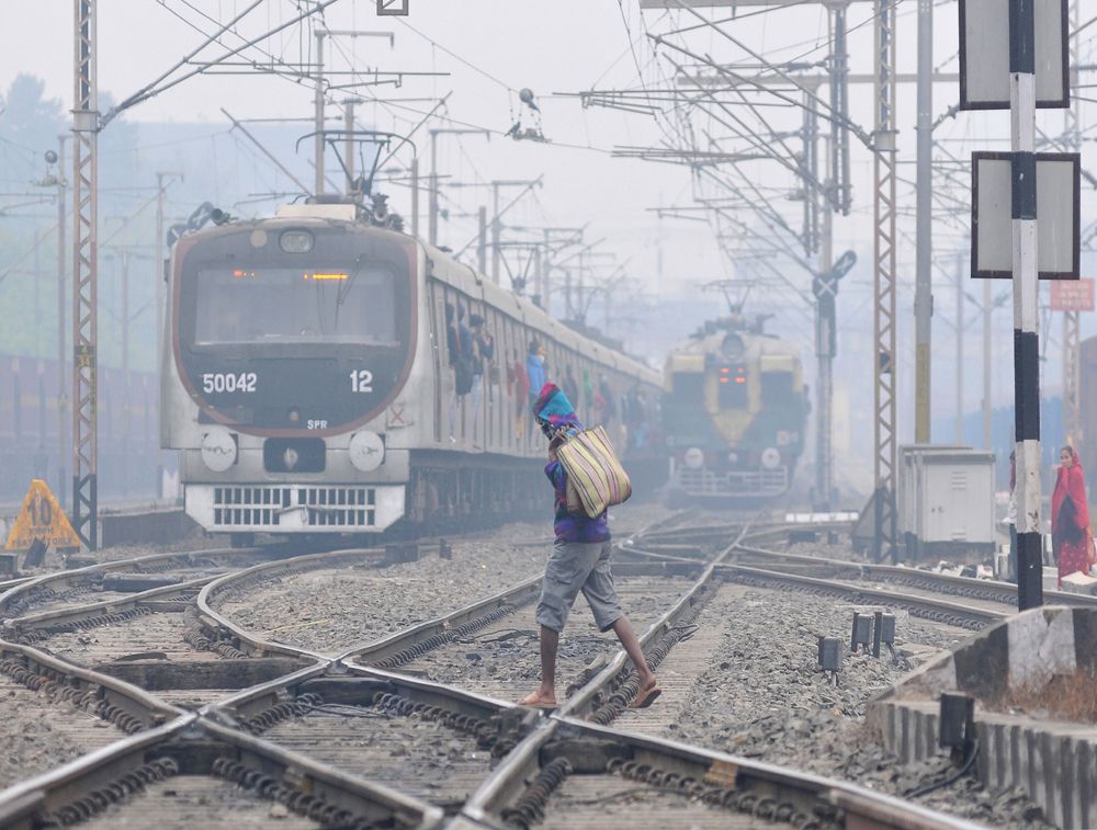 A man crosses the tracks as two trains approach a junction on a cold and wintery morning in Calcutta on January 2