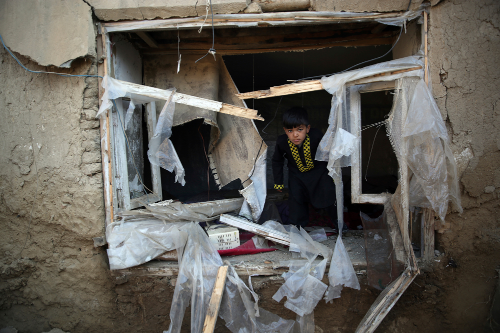 A boy inspects his damaged home after after an attack near the Bagram Air Base in Kabul on December 11