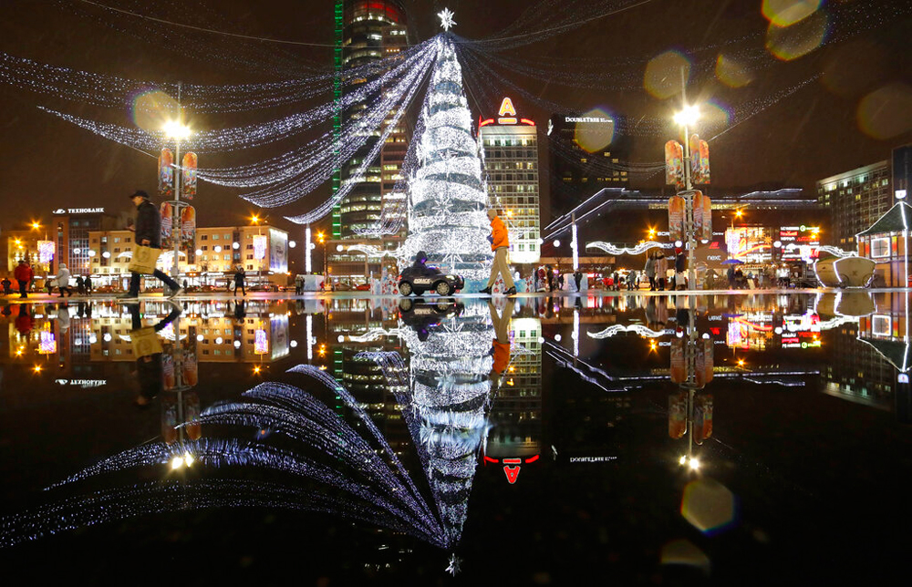 A New Year tree is reflected in a pond as people walk on the square in Minsk, Belarus, on December 26