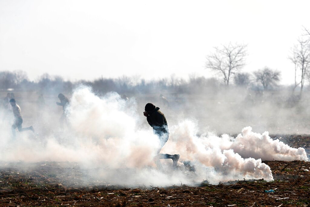 Migrants run to avoid tear gas thrown by Greek police during clashes in Edirne, at the Turkish-Greek border, on March 2