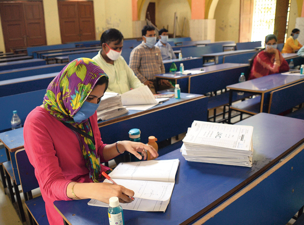 Government schoolteachers practise social distance as they check matriculation answer sheets at the Zilla School in Ranchi on Thursday. Apart from sitting away from each other, teachers who on Thursday started to evaluate the answer sheets of Class X board examinees under the Jharkhand Academic Council also wore masks and kept sanitisers near them as they worked. Both matriculation and intermediate exams were held in February, but the onset of the Covid19 pandemic in the state in March put evaluation on hold and delayed results.