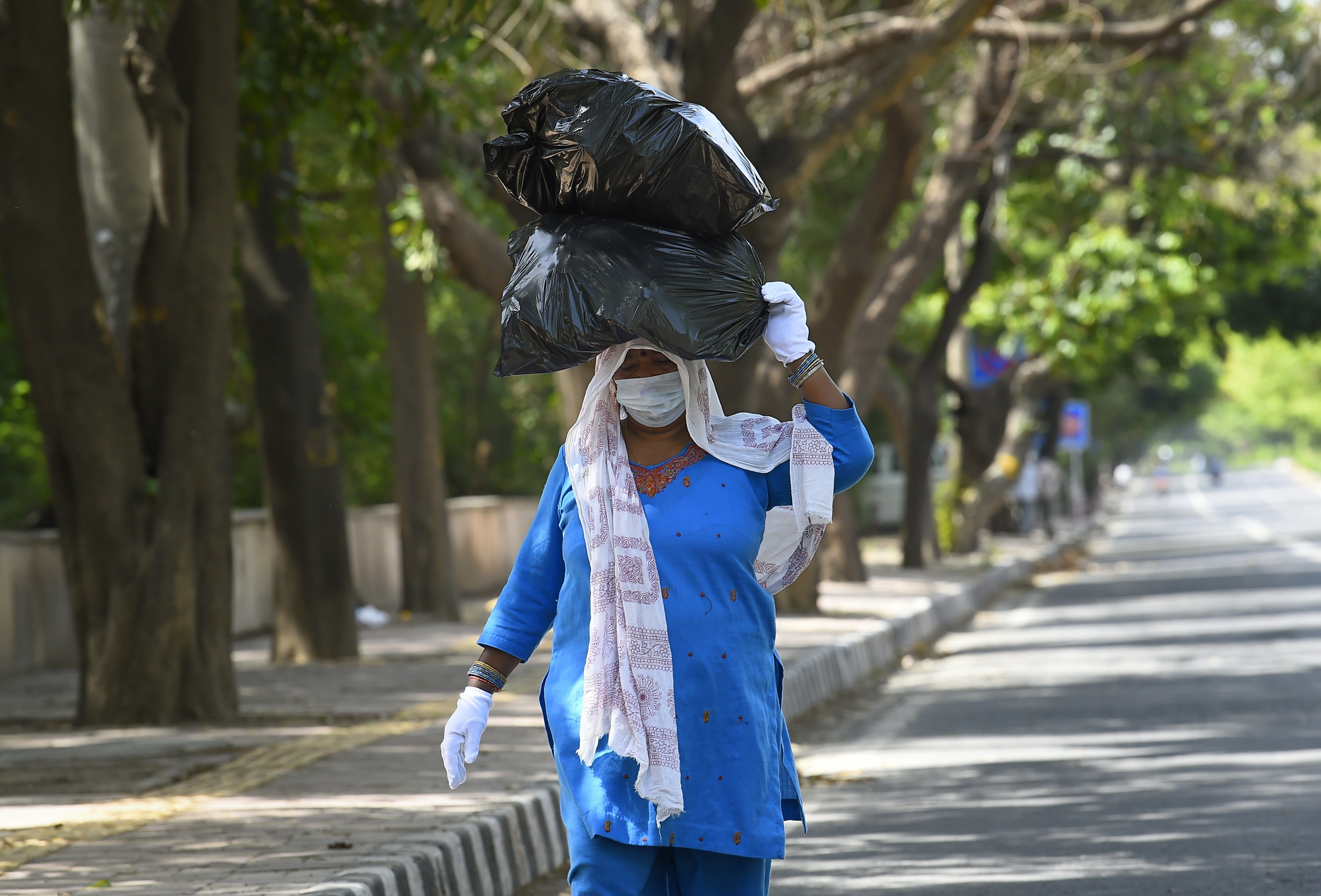 A woman, wearing face mask and gloves, walks on a road during the nationwide complete lockdown imposed in a bid to contain the coronavirus pandemic, in New Delhi, Tuesday, March 31, 2020