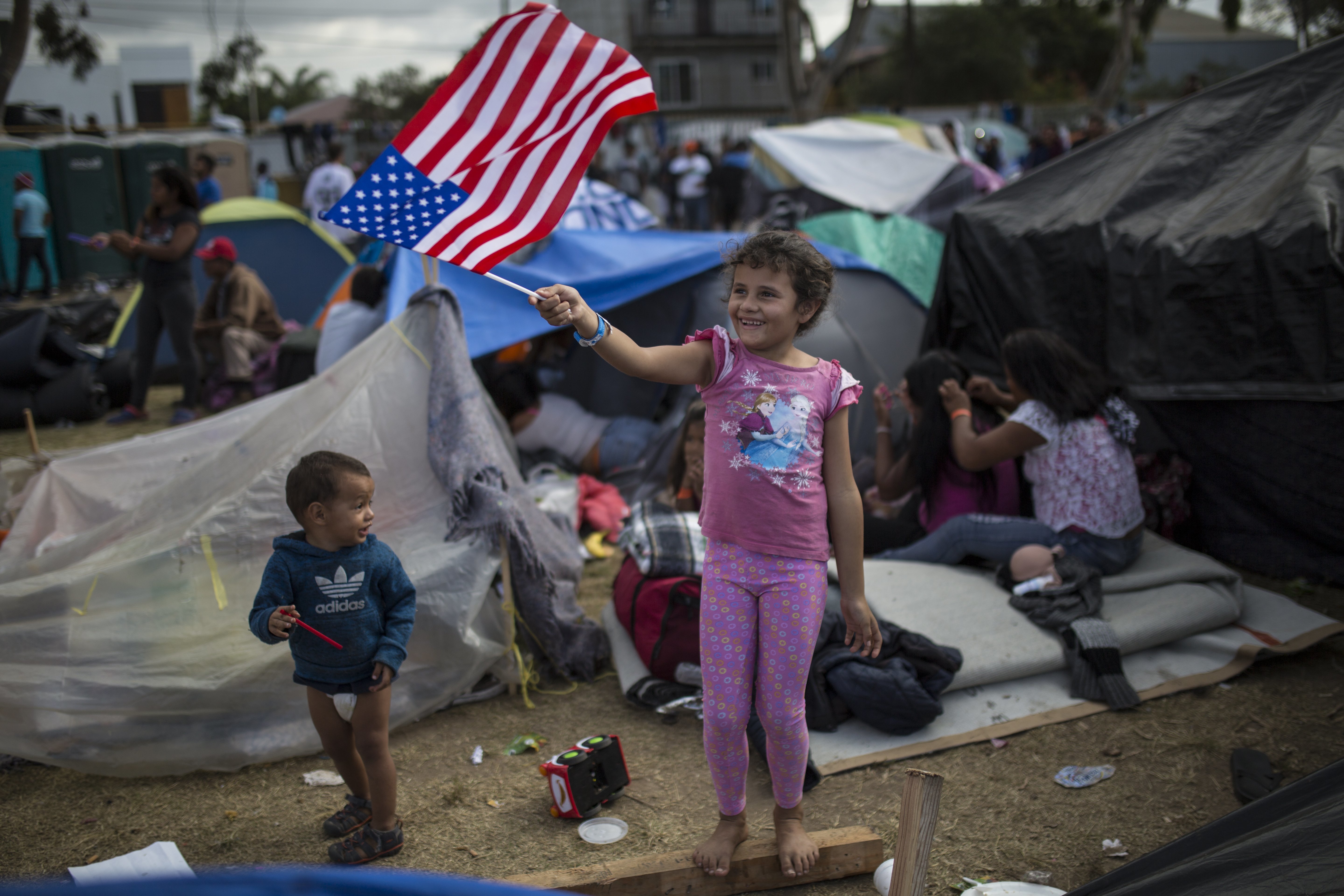 Seven-year-old Honduran migrant Genesis Belen Mejia Flores waves an American flag near the Benito Juarez Sports Center serving as a temporary shelter for Central American migrants, in Tijuana, Mexico.