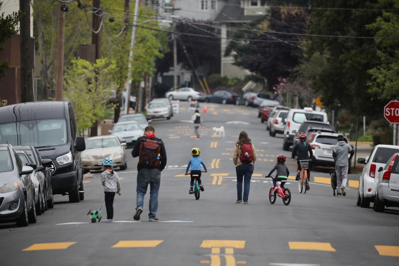 Pedestrians walk and bike on a section of 42nd Street in Oakland, Calif., that was closed off to traffic during the coronavirus outbreak, on April 11, 2020.