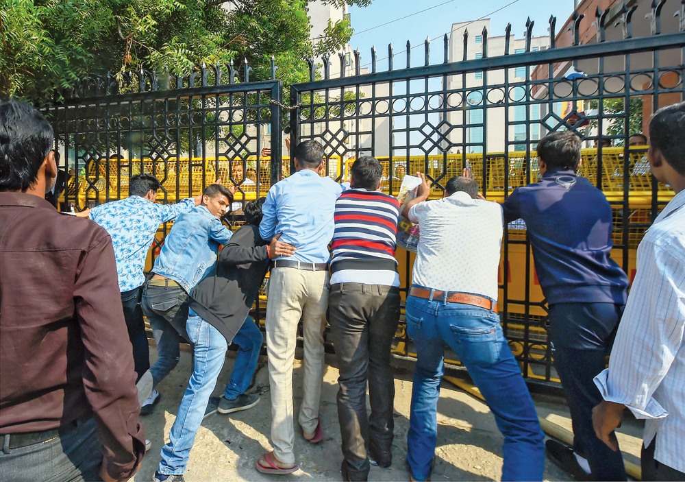 People try to push open the main gate of the Saket district court complex in New Delhi on Wednesday after it was locked by lawyers on strike