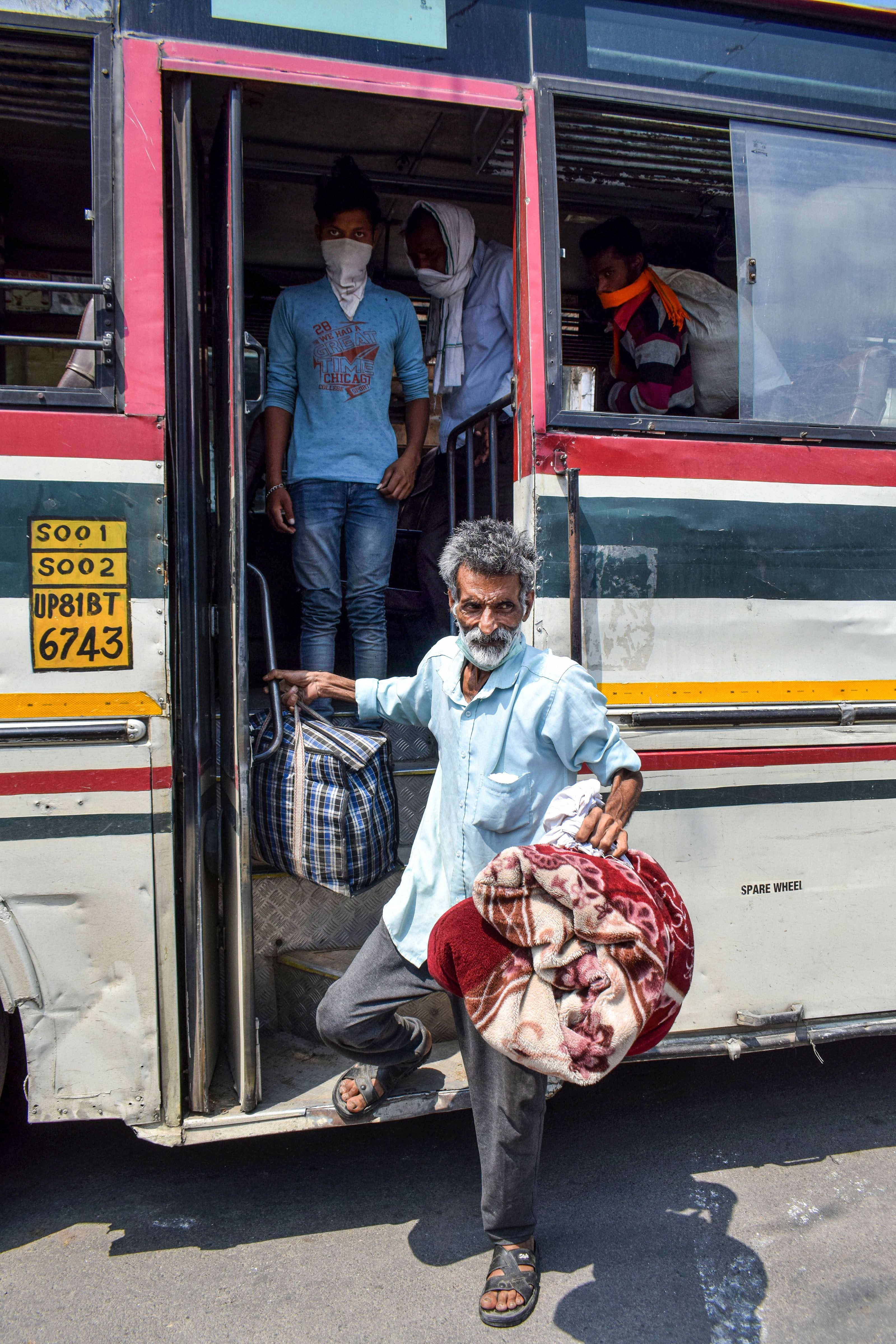 Migrant labourers from Uttar Pradesh who were stranded in Haryana alight from the bus arranged by UP government as they arrive outside a quarantine centre, as a preventive measure against the coronavirus pandemic, in Prayagraj, Monday, April 27, 2020.