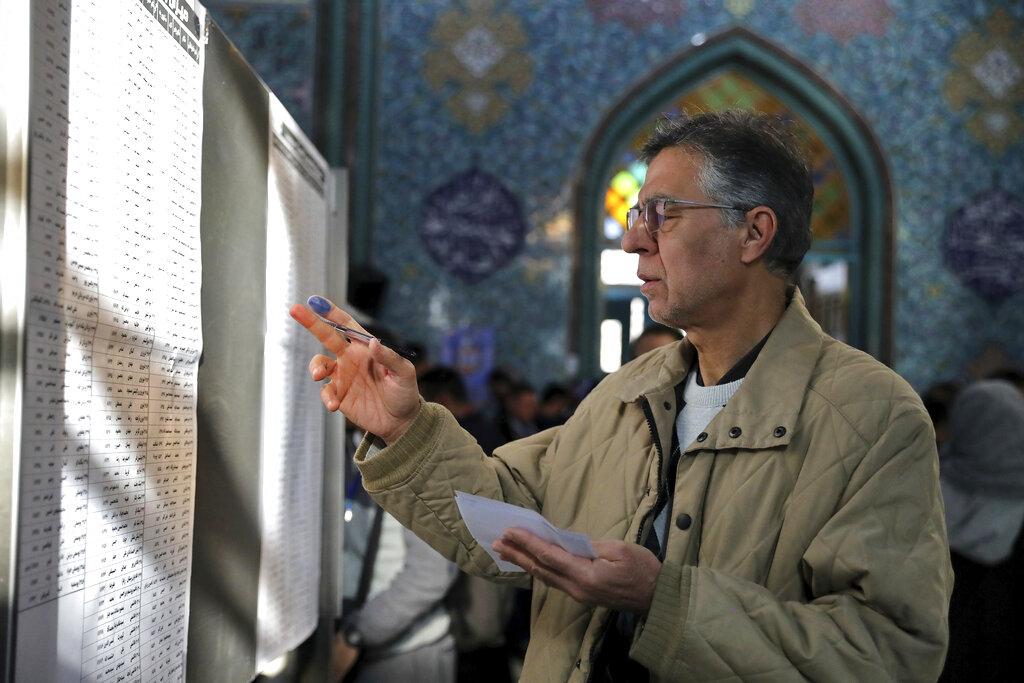 A voter fills out his ballot in the parliamentary elections at a polling station in Tehran, Iran, on Friday