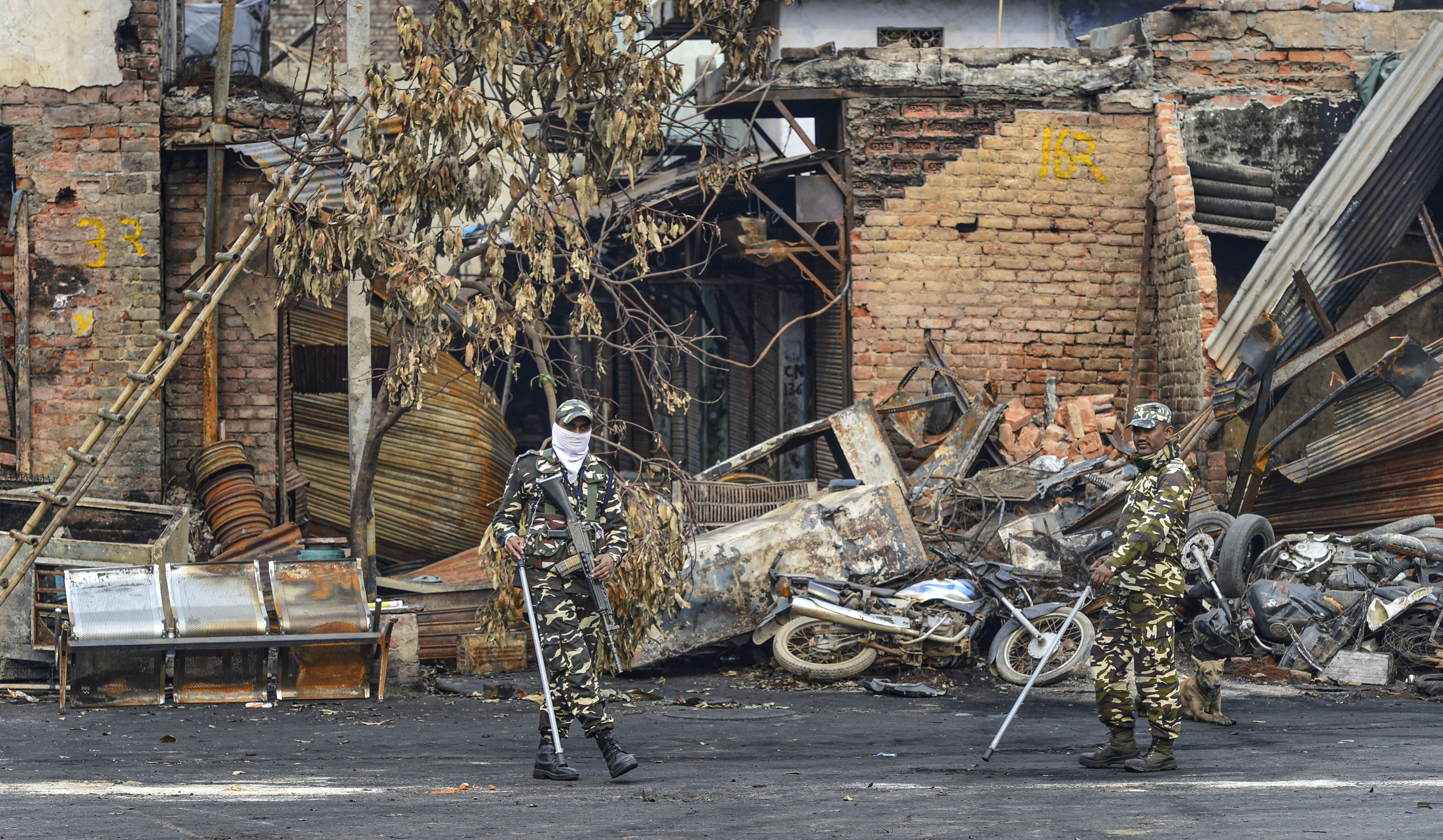 Sashastra Seema Bal personnel walk past burnt and damaged shops, which were allegedly set on fire by miscreants during communal violence last week, at Gokalpuri market in northeast Delhi, Wednesday, March 4, 2020.