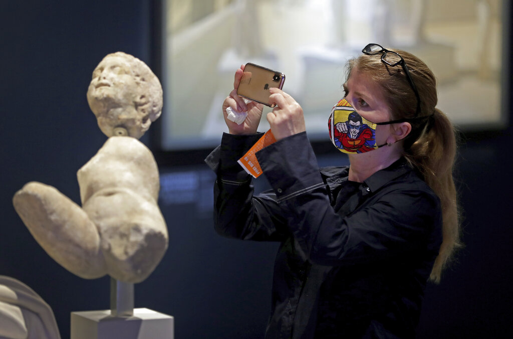 A woman takes a picture of a sculpture at the 'Pergamonmuseum The Panorama' in Berlin, Germany, Tuesday, May 12, 2020. After weeks of lockdown due to the new coronavirus outbreak Berlin's museums opened the doors for visitors on Tuesday. 