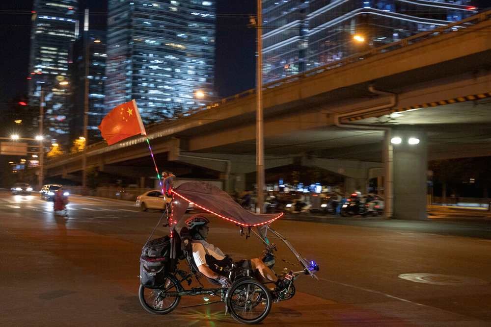 A cyclist with a Chinese national flag rides through the Central Business District in Beijing on Wednesday