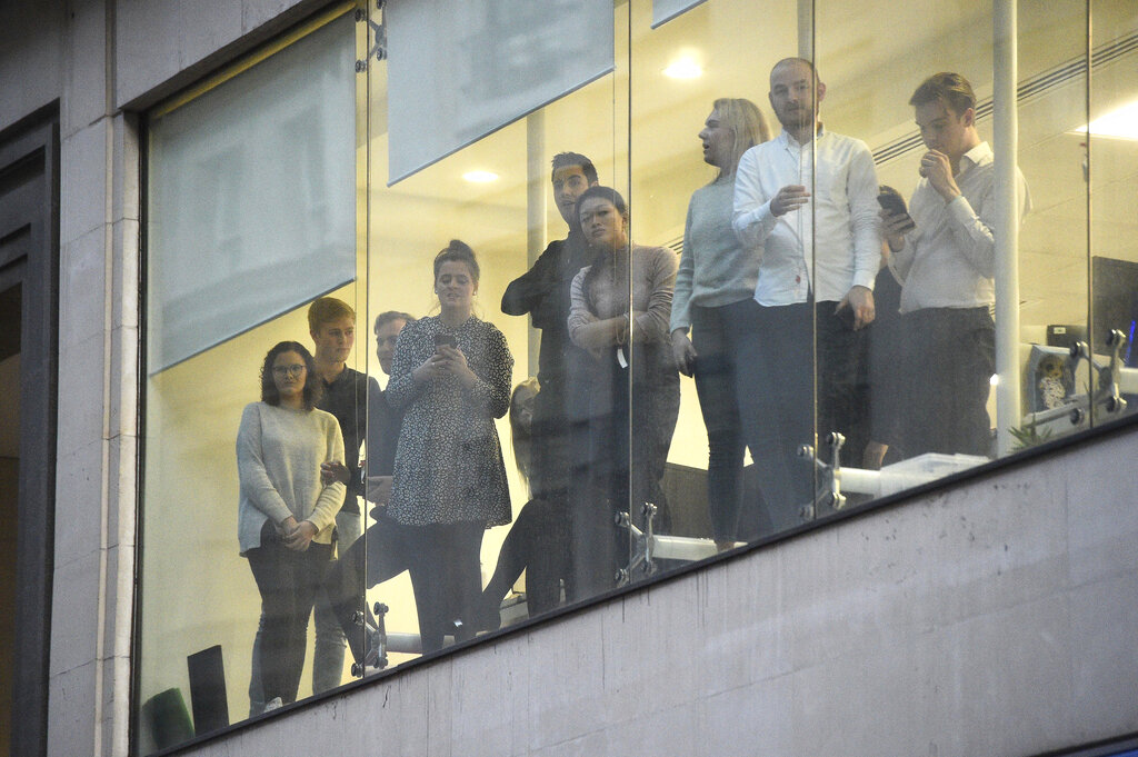 Office workers watching police near the scene of an incident on London Bridge in central London, Friday, Nov. 29, 2019. 