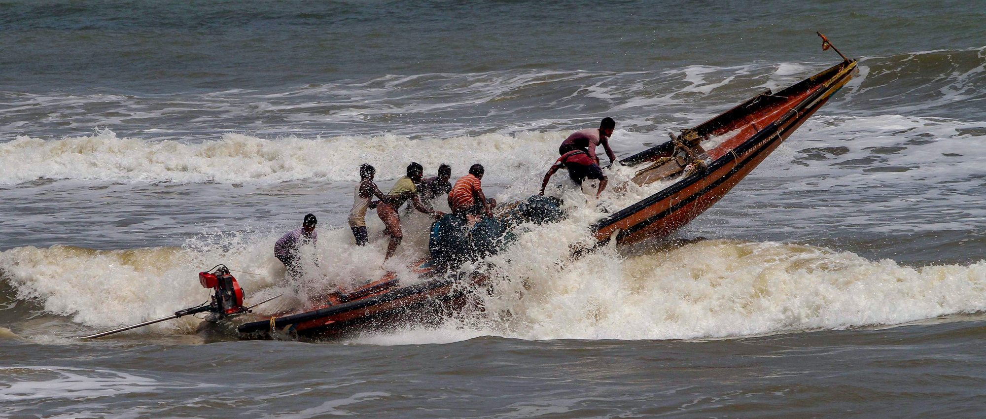 Fishermen try to control their boat amidst rough sea waters at Puri beach on Tuesday, April 30 2019. 