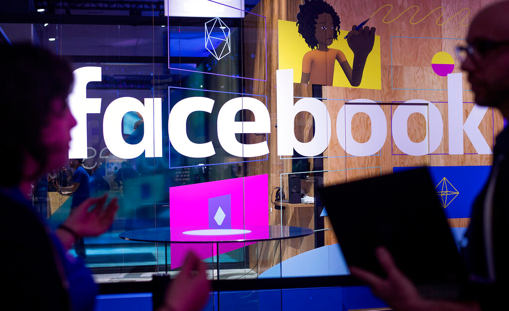 In this April 18, 2017 file photo, conference workers speak in front of a demo booth at Facebook's annual F8 developer conference, in San Jose, California.