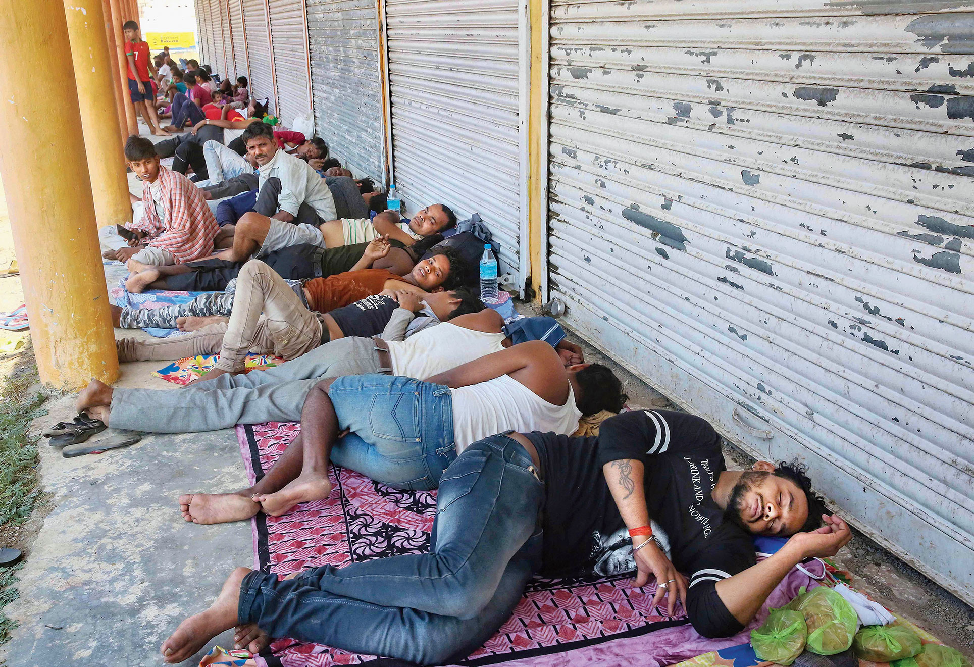 Migrants on their way back to Uttar Pradesh from Maharashtra rest at a market along a highway in Bhopal on Tuesday.