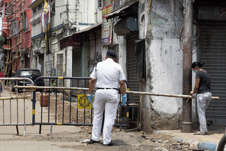 A woman on her way home from the market tried to remove a bamboo barricade, set up by police to restrict pedestrians as part of the drive against Covid-19, in Bowbazar 