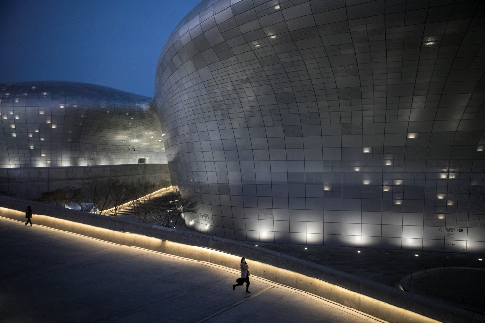 People walk through Dongdaemun Design Plaza in the city center of Seoul, South Korea on March 20, 2020