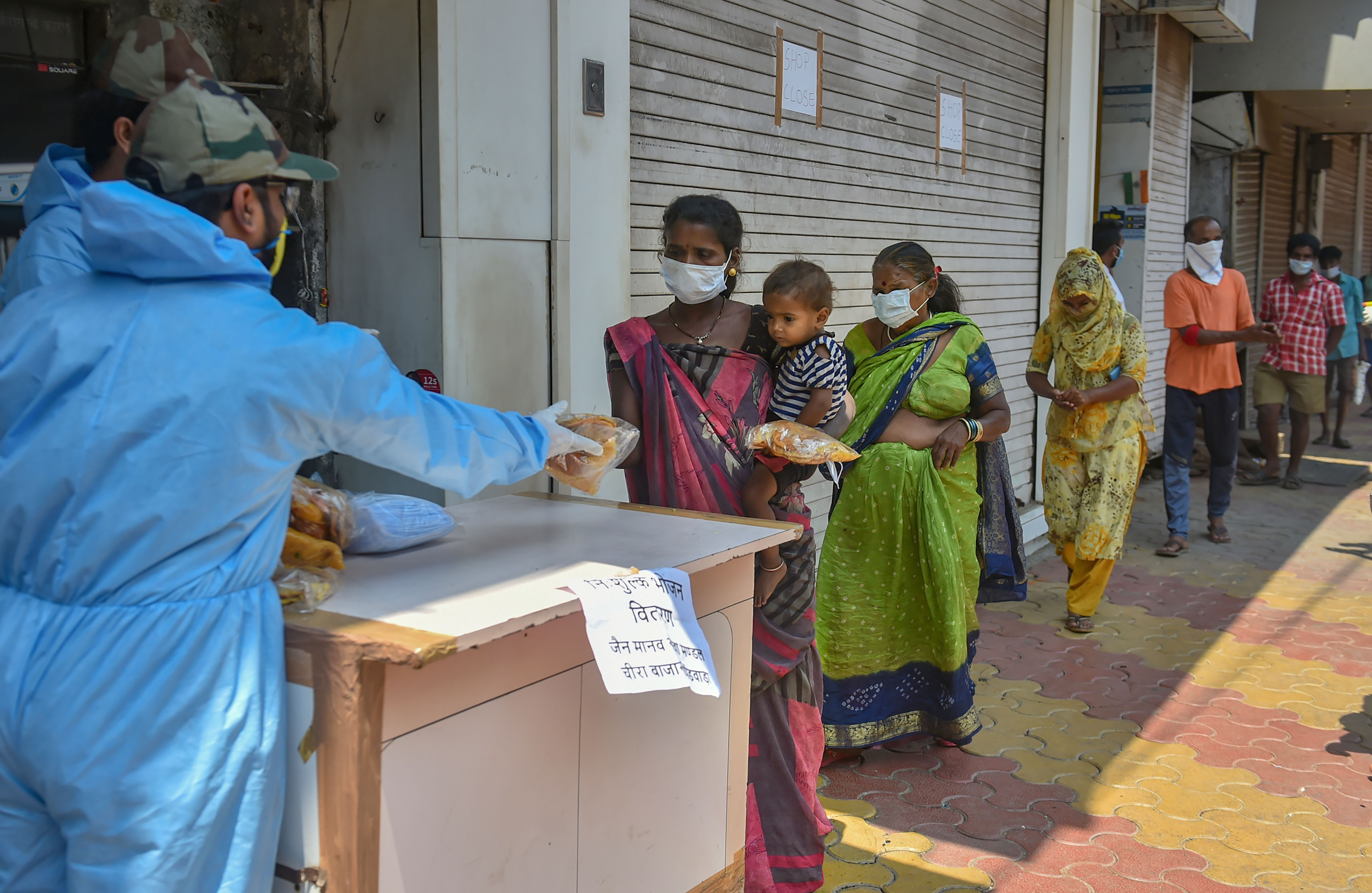 Volunteers distribute packaged food among homeless people during a nationwide lockdown in the wake of the coronavirus pandemic, at Kalbadevi area in Mumbai, Sunday, March 29, 2020