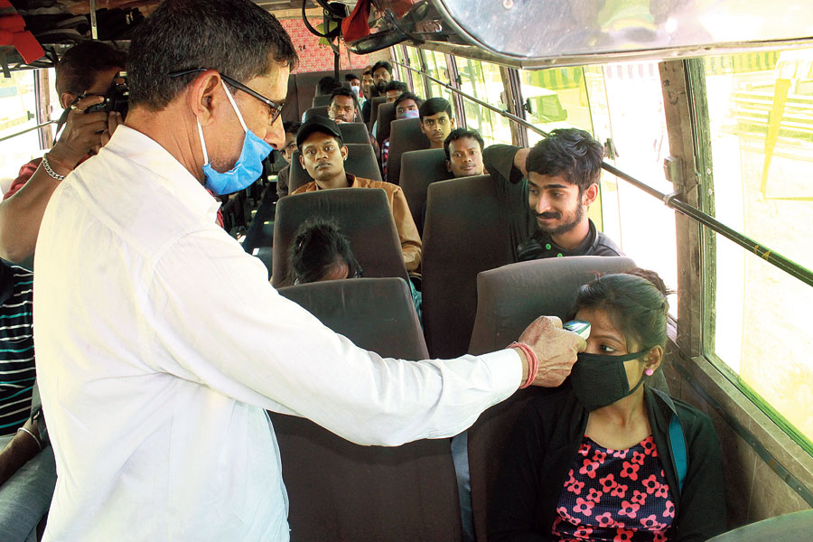 HEAT CHECK:  Passengers in a bus undergo thermal screening at a check-point set up by district administration at Domuhani bridge in Jamshedpur on Friday. 