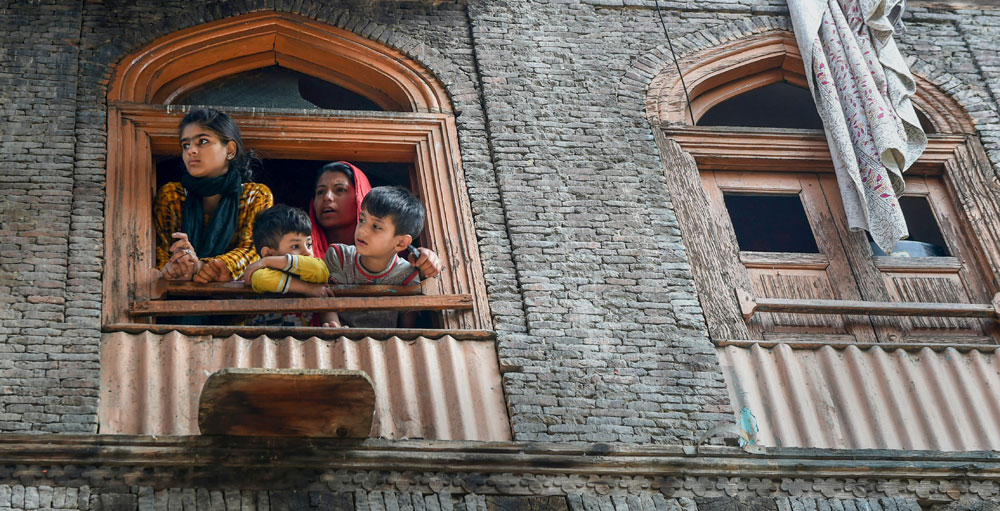 Woman and children watch as police arrive at the spot where two National Conference workers were allegedly shot dead by militants, three days ahead of the first phase of elections for urban local bodies, at Karfali Mohalla in Down Town, Srinagar on Friday.