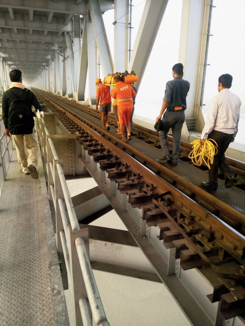 The NDRF personnel walk with the rescued youth before boarding a train