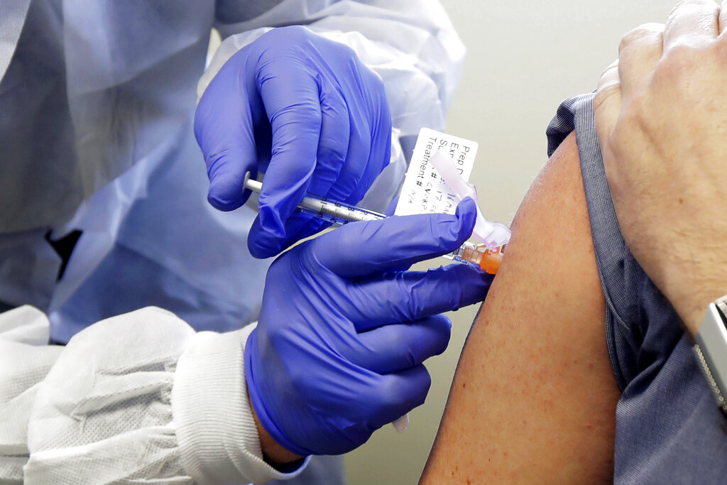 In this Monday, March 16, 2020 file photo, a patient receives a shot in the first-stage study of a potential vaccine for COVID-19, the disease caused by the new coronavirus, at the Kaiser Permanente Washington Health Research Institute in Seattle.
