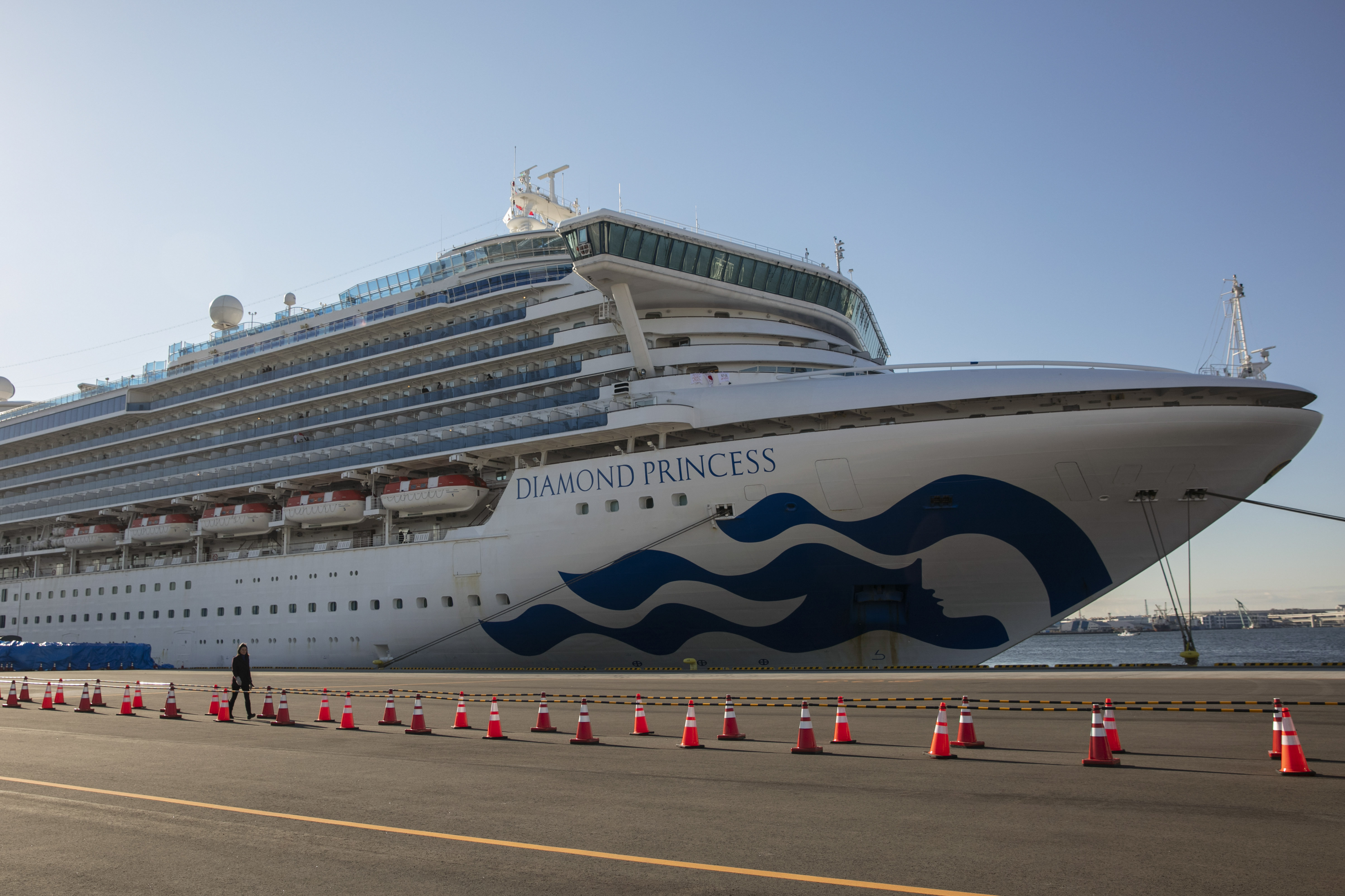 A reporter walks near the quarantined Diamond Princess cruise ship in Yokohama, near Tokyo, on Tuesday