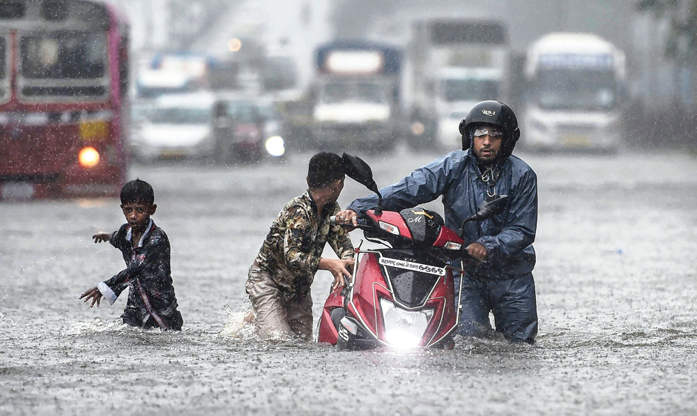 People wade through a waterlogged street at Ghatkopar